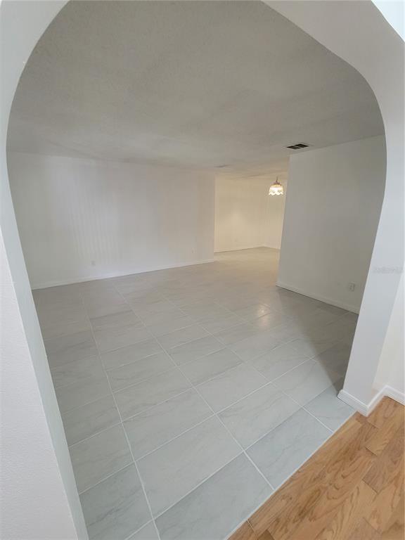 An arched doorway leads into a bright room with light gray tile flooring — 4825 SQUIRES DRIVE, TITUSVILLE, FL