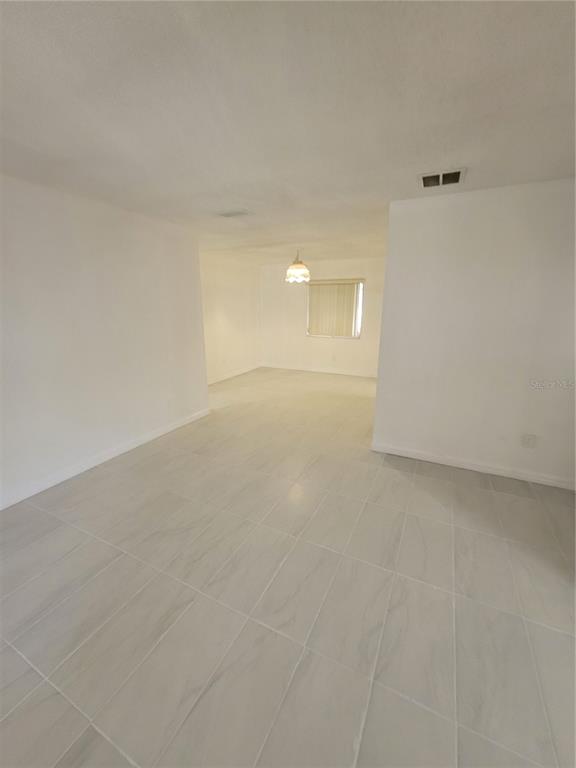 An open-concept room with white walls and light-colored tile flooring featuring a single window — 4825 SQUIRES DRIVE, TITUSVILLE, FL