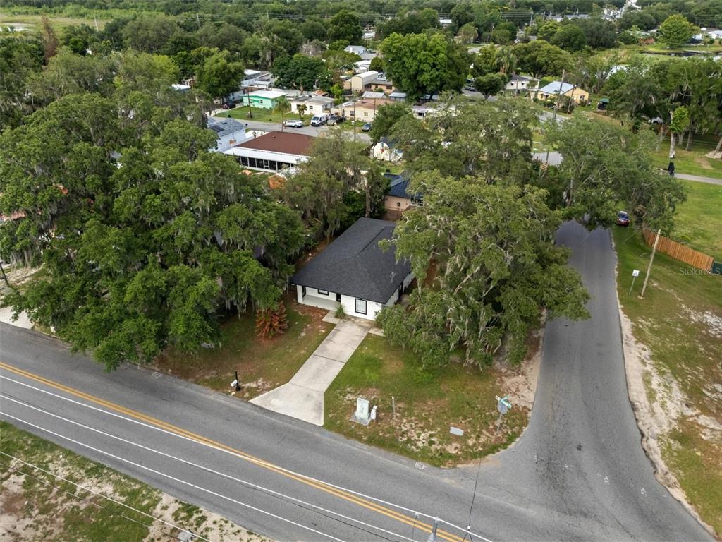 An aerial view shows a white house with a dark roof surrounded by large trees — 1001 PRADO GRANDE AVENUE, HAINES CITY, FL
