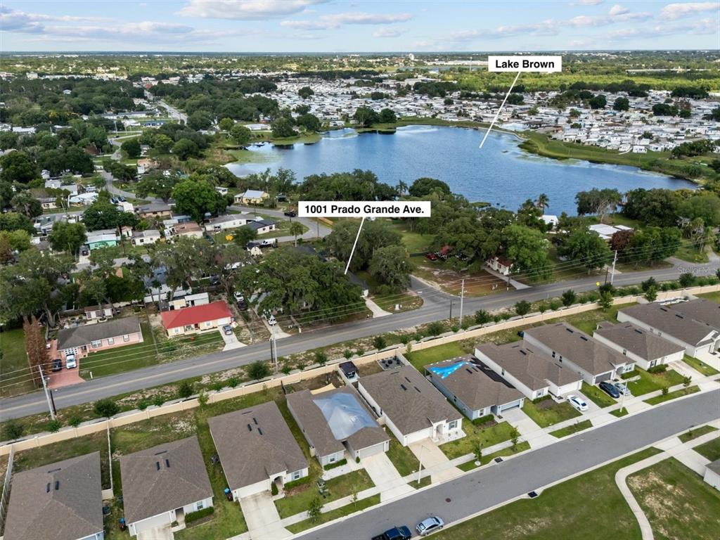 An aerial view shows a residential neighborhood with a lake and a marked property — 1001 PRADO GRANDE AVENUE, HAINES CITY, FL