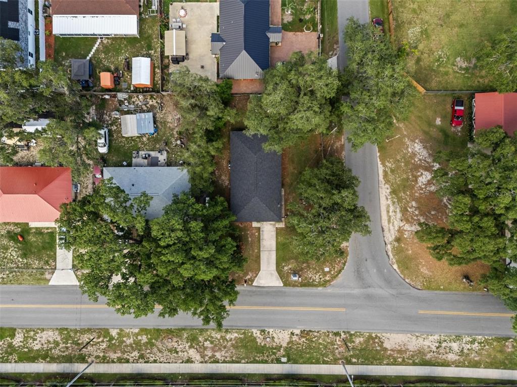 An aerial view shows a house with a dark roof, a driveway, and surrounding trees — 1001 PRADO GRANDE AVENUE, HAINES CITY, FL