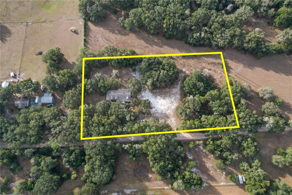 A two-story log cabin home features a stone foundation, a front porch, and dormer windows — 6892 SWAIN ROAD, SORRENTO, FL