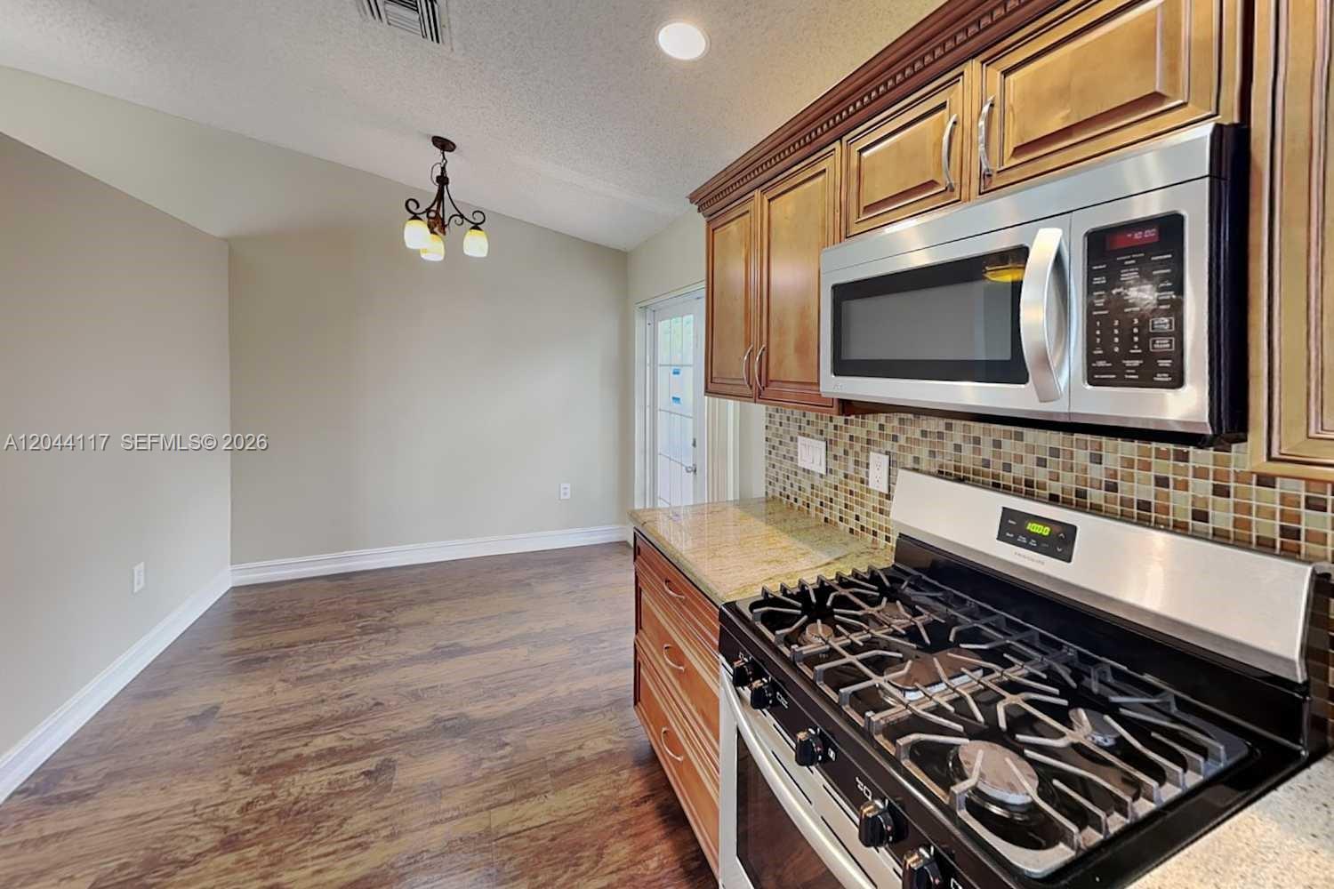 A kitchen features wood cabinets, a gas stove, a microwave, and a dining area — PLANTATION, FL