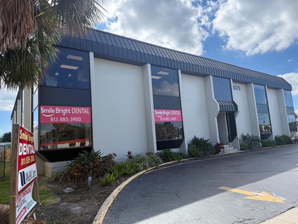 A two-story commercial building with a dental office sign and a paved parking lot — 8370 W HILLSBOROUGH AVENUE UNIT 206, TAMPA, FL