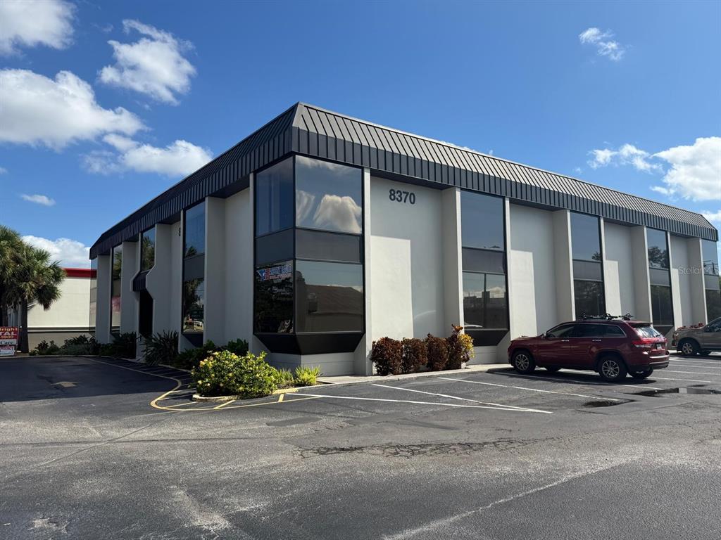 A two-story commercial office building with dark-tinted windows and a parking lot in front — 8370 W HILLSBOROUGH AVENUE UNIT 206, TAMPA, FL