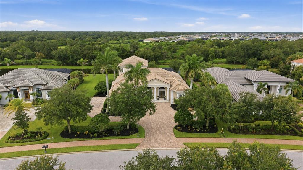 An aerial view shows a large suburban house with a paved driveway and palm trees — 3360 FOUNDERS CLUB DRIVE, SARASOTA, FL