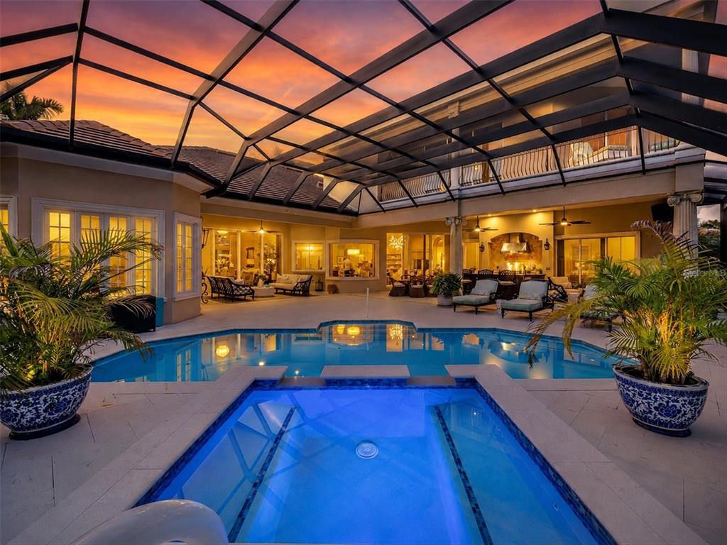A covered patio features a swimming pool, a hot tub, and outdoor seating at sunset — 3360 FOUNDERS CLUB DRIVE, SARASOTA, FL