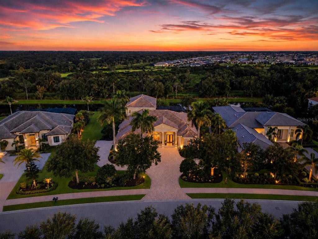 An aerial view of a large residential home with a paved driveway at sunset — 3360 FOUNDERS CLUB DRIVE, SARASOTA, FL