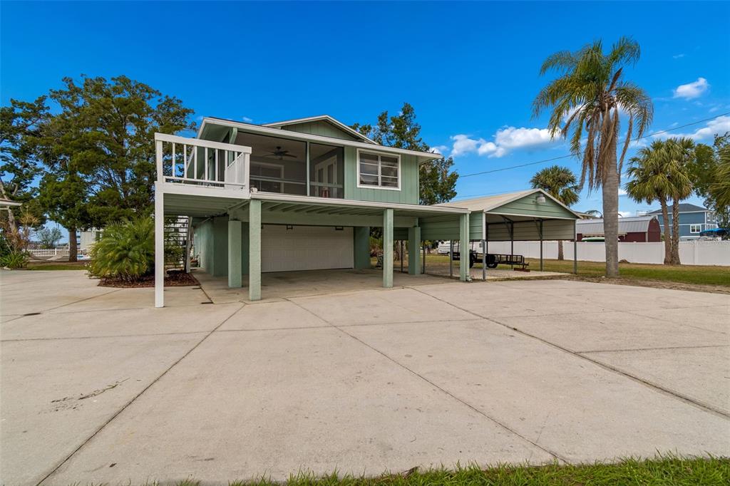 A two-story house on stilts features a screened balcony, a garage, and an attached carport — 14539 COFFEY LANE, HUDSON, FL