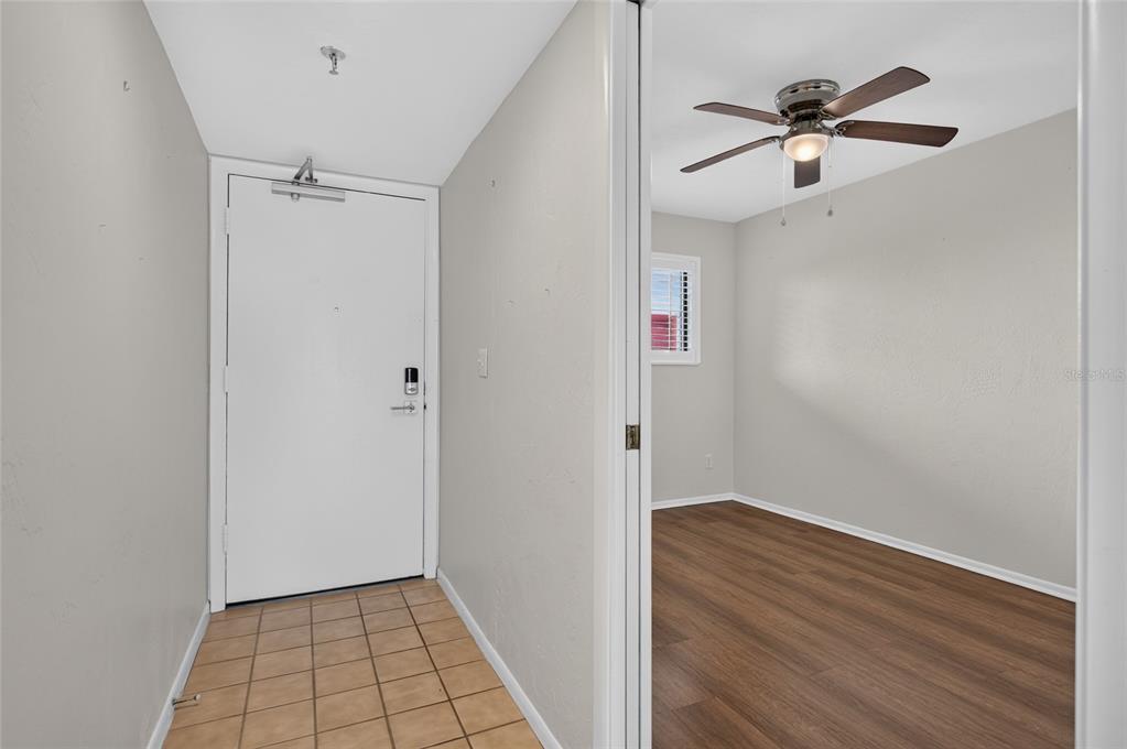An entryway with tiled floors leads to a room with wood-look flooring and a ceiling fan — 3001 S ATLANTIC AVENUE UNIT 433, NEW SMYRNA BEACH, FL