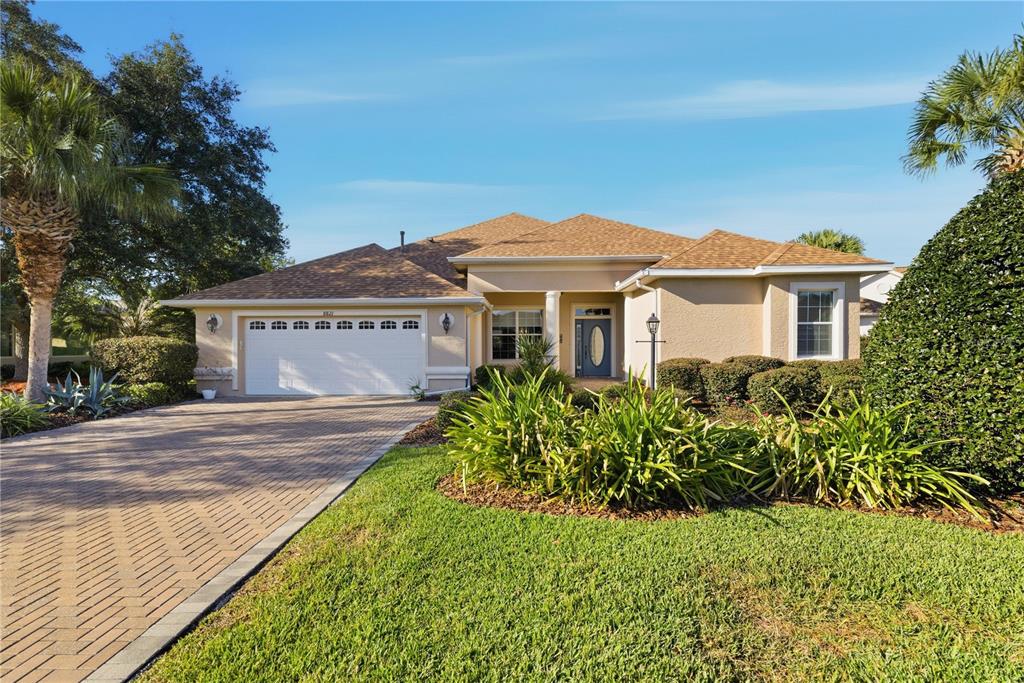 A single-story house with a beige stucco exterior, a paved driveway, and a two-car garage — 8821 SW 82ND COURT ROAD, OCALA, FL