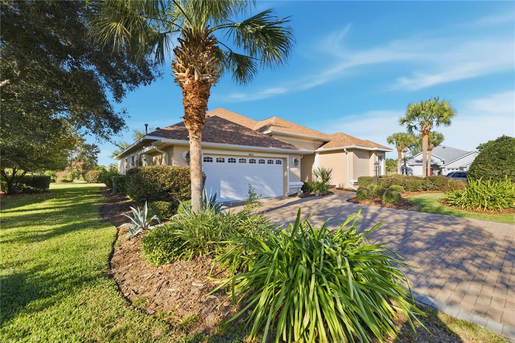 A single-story house with a paved driveway, a two-car garage, and palm trees — 8821 SW 82ND COURT ROAD, OCALA, FL