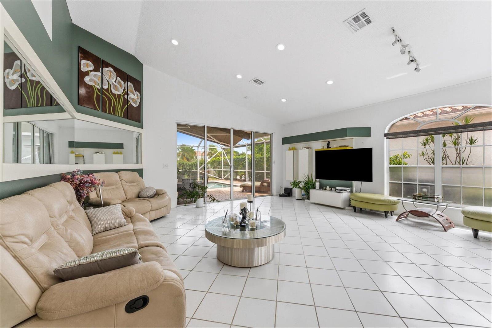 A bright living room features white tile floors, a vaulted ceiling, and sliding glass doors — 3938 Redondo Court, Boca Raton FL 33487, BOCA RATON, FL