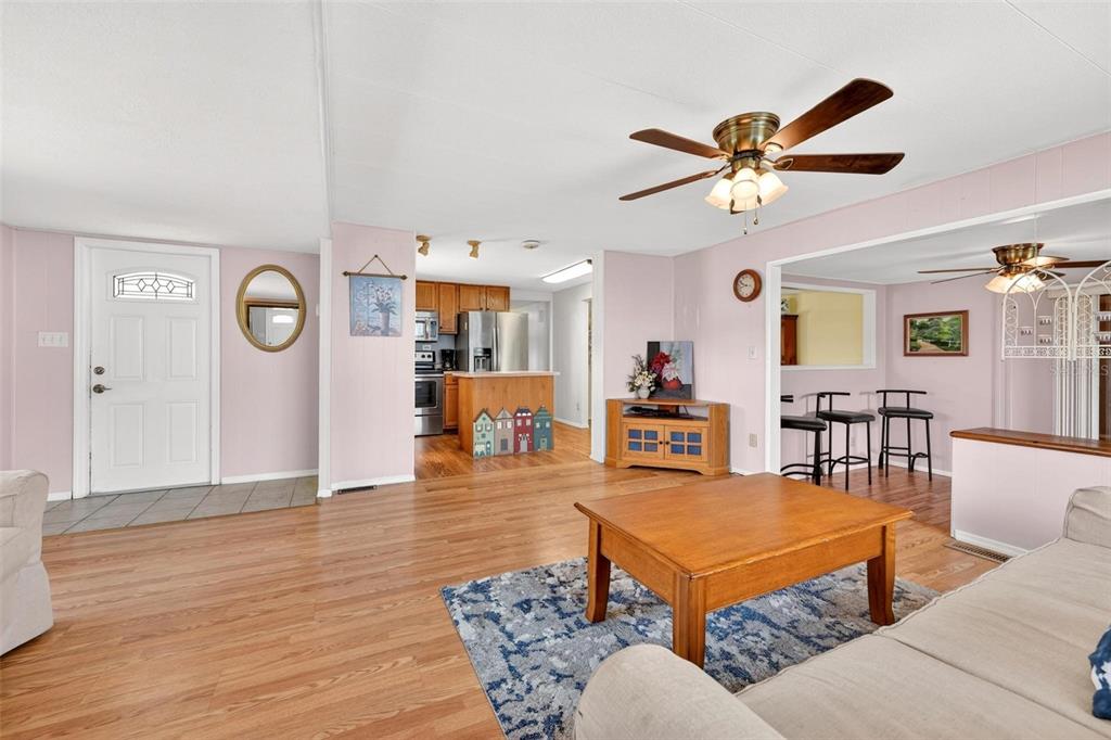 A living room with light wood flooring, a ceiling fan, and an open kitchen beyond — 31643 HOWARD STREET, TAVARES, FL