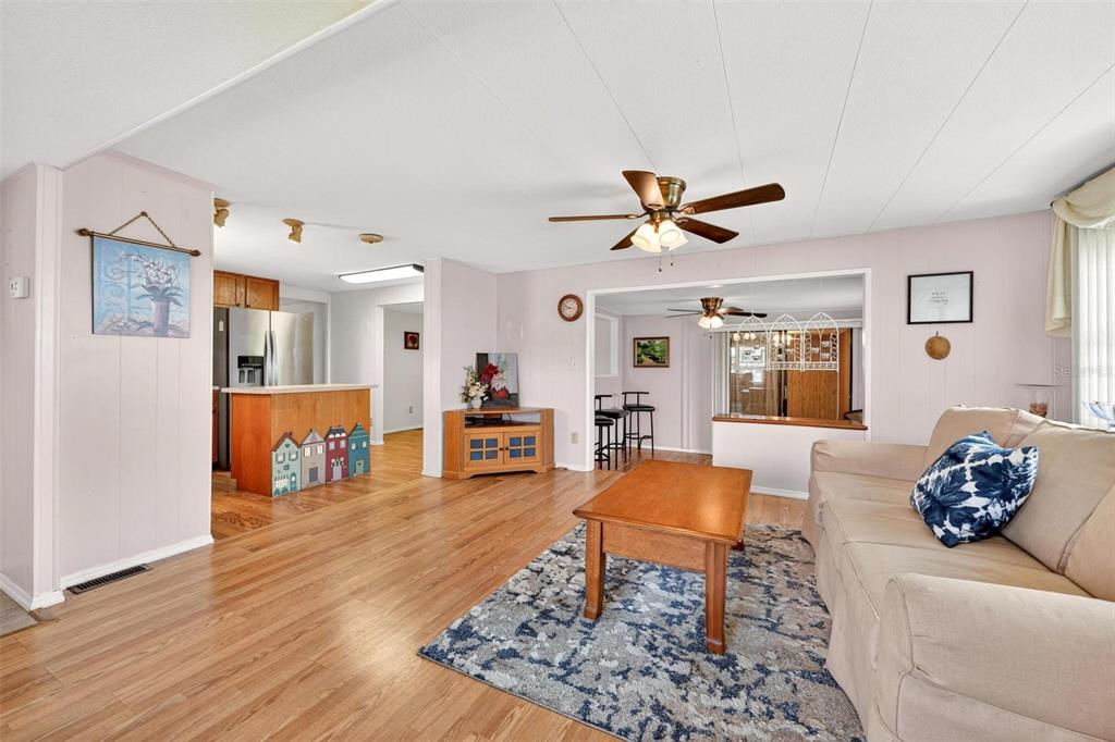 A living room with light wood floors, a beige sofa, and an open kitchen area — 31643 HOWARD STREET, TAVARES, FL