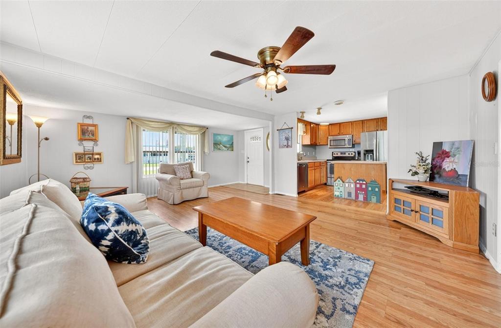 A living room with wood flooring, a ceiling fan, and an open kitchen in the background — 31643 HOWARD STREET, TAVARES, FL