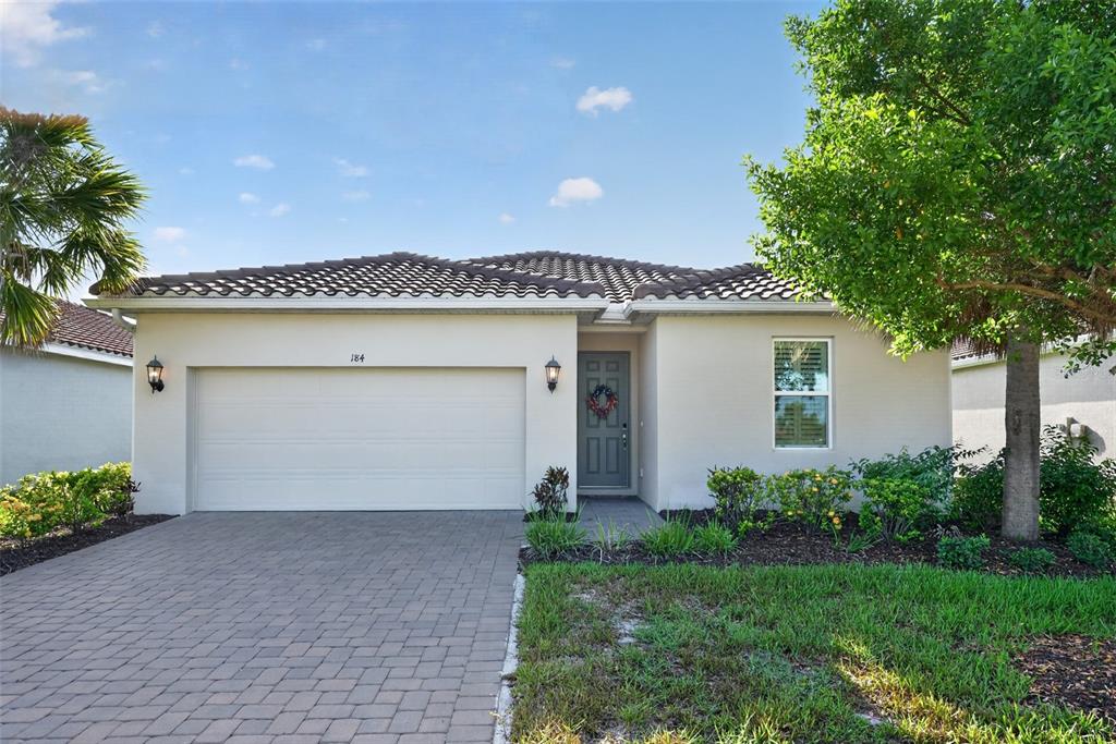 A single-story house with a beige stucco exterior, a two-car garage, and a paved driveway — 184 DAYLILY BOULEVARD, NOKOMIS, FL