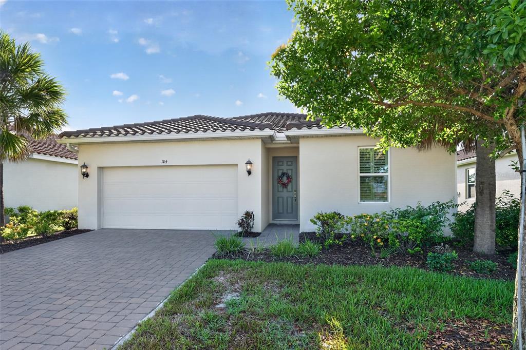 A single-story house with a beige stucco exterior, a two-car garage, and a paved driveway — 184 DAYLILY BOULEVARD, NOKOMIS, FL
