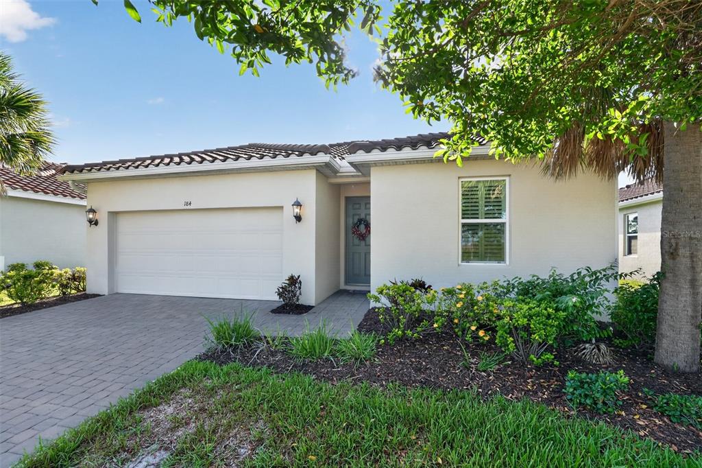 A single-story house with a white stucco exterior, a two-car garage, and a paved driveway — 184 DAYLILY BOULEVARD, NOKOMIS, FL