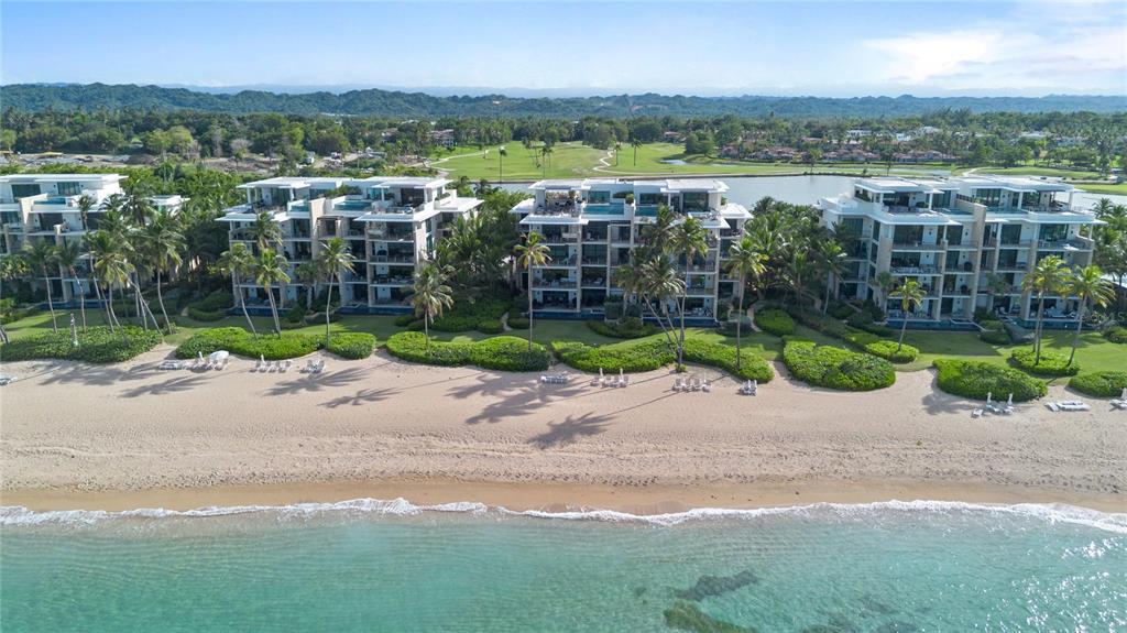 An aerial view shows four modern beachfront apartment buildings with balconies overlooking a sandy beach — 200 Dorado Beach Drive 3731 WEST BEACH, A RITZ-CARLTON RESIDENCES UNIT 3731, DORADO, PR