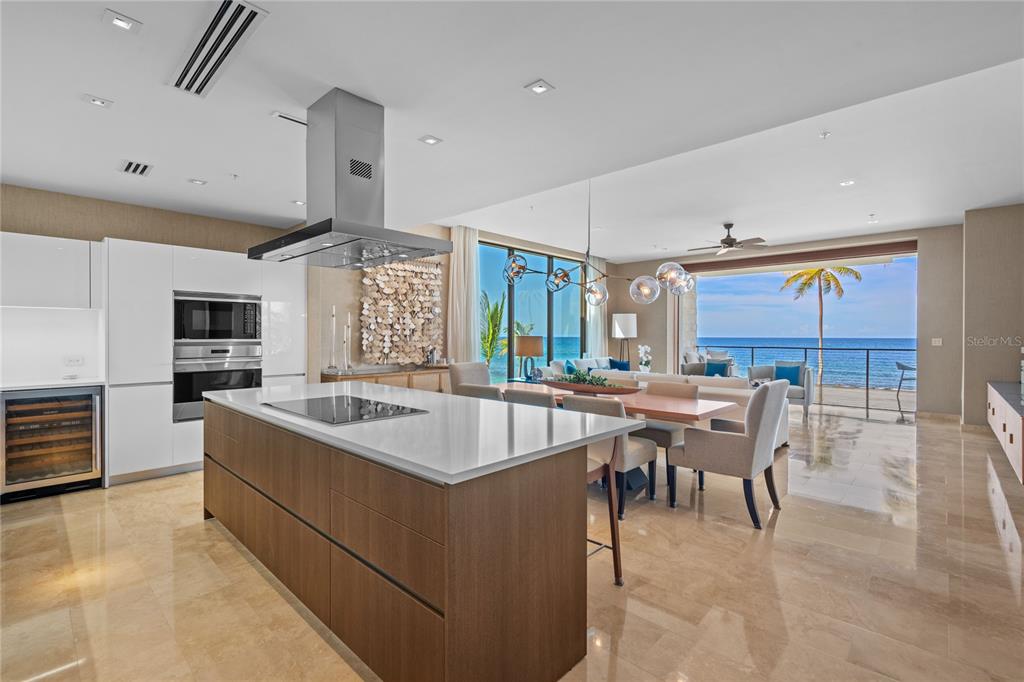 A modern kitchen with a wood island and white cabinets opens to a beachside living area — 200 Dorado Beach Drive 3731 WEST BEACH, A RITZ-CARLTON RESIDENCES UNIT 3731, DORADO, PR