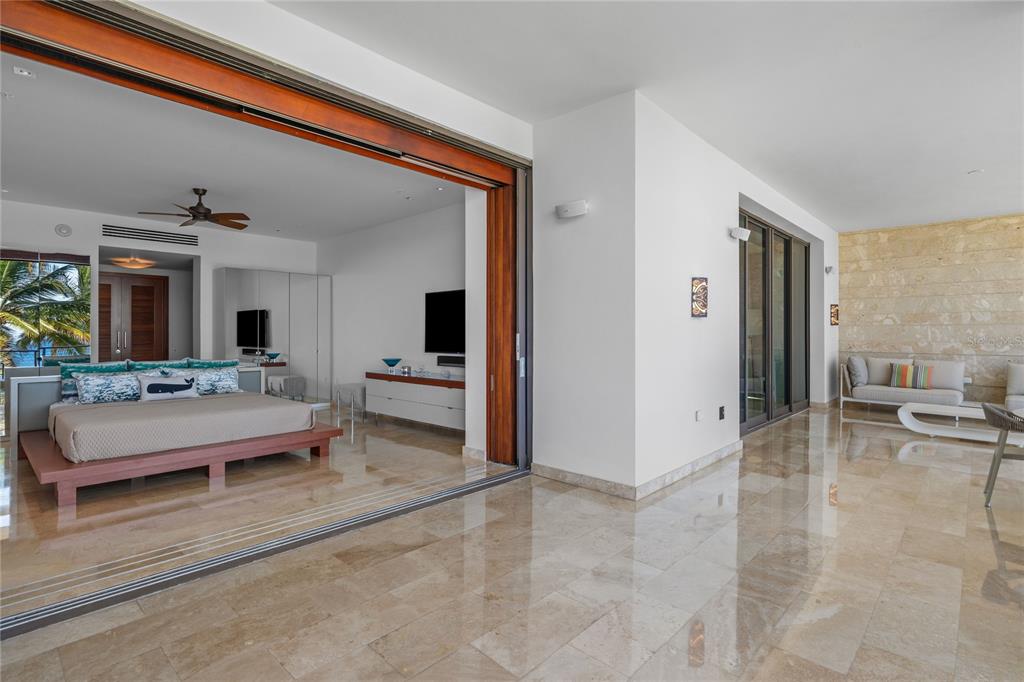 A bedroom with a large bed opens onto a spacious, tiled outdoor patio area — 200 Dorado Beach Drive 3731 WEST BEACH, A RITZ-CARLTON RESIDENCES UNIT 3731, DORADO, PR