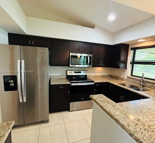 A kitchen with dark wood cabinets, granite countertops, stainless steel appliances, and light tile flooring — 20 NE 20th Ave, Cape Coral FL 33909, CAPE CORAL, FL