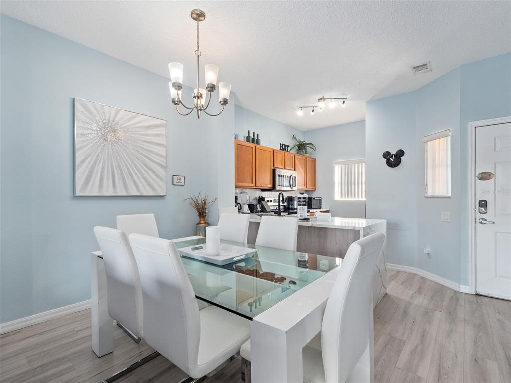 A dining area with a glass table and white chairs sits adjacent to a kitchen — 136 POMPANO BEACH DRIVE, KISSIMMEE, FL