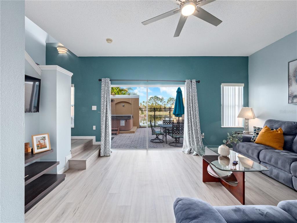 A living room with light wood floors, blue walls, and a sliding door to a patio — 136 POMPANO BEACH DRIVE, KISSIMMEE, FL