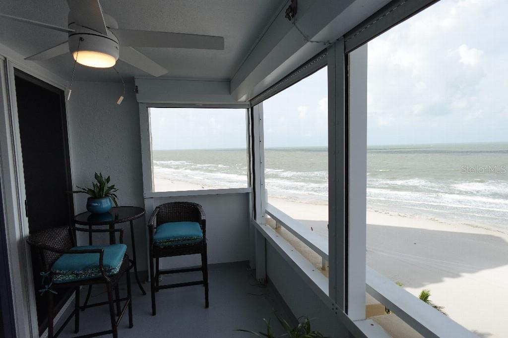 A screened-in balcony features a ceiling fan, patio furniture, and a direct ocean view — 17920 GULF BOULEVARD UNIT 803, REDINGTON SHORES, FL