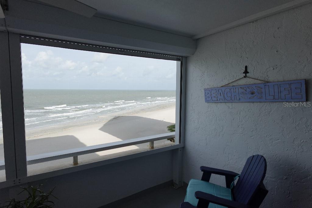 A balcony with a blue chair overlooks a sandy beach and the ocean — 17920 GULF BOULEVARD UNIT 803, REDINGTON SHORES, FL