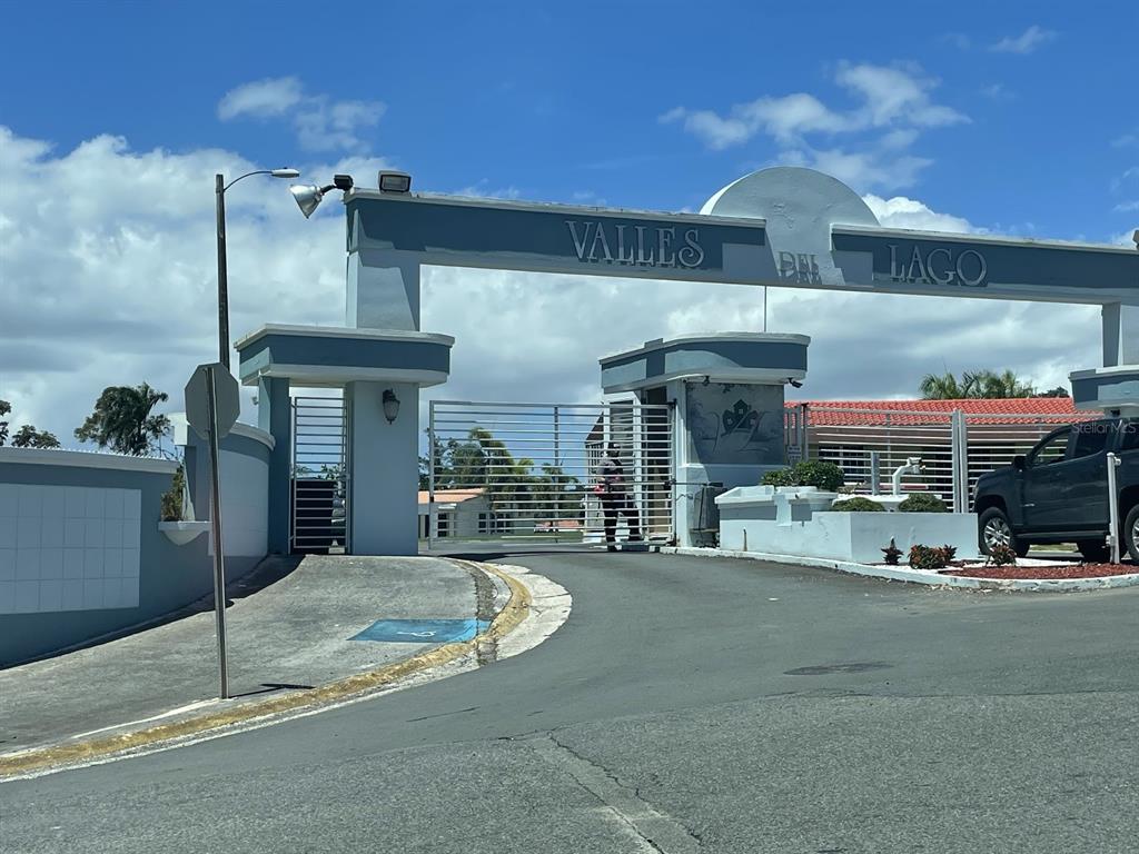The entrance to Valles del Lago features a gated community sign and a metal security gate — CALLE CARRAIZO, CAGUAS, PR