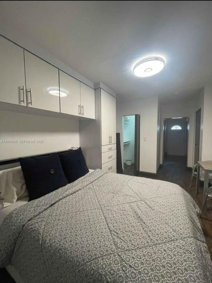 A bedroom features a bed with a patterned comforter, overhead storage cabinets, and a closet — 315 NW 59th St # 1, Miami FL 33127, MIAMI, FL