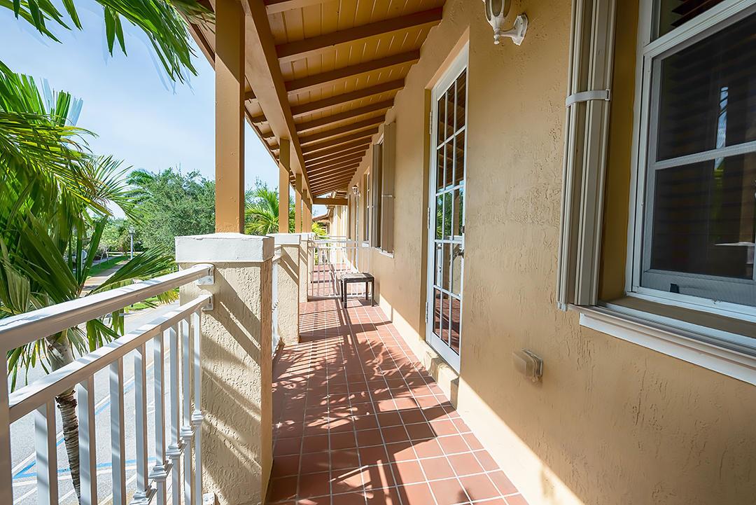 A covered balcony features terracotta tile flooring, white railings, and a view of palm trees — 2502 NW 4th Street, Boynton Beach FL 33426, BOYNTON BEACH, FL