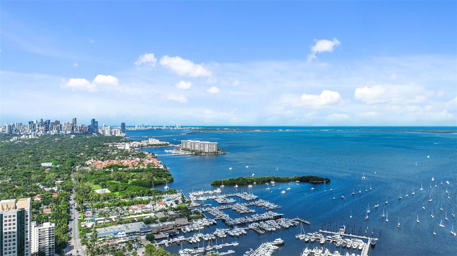 An aerial view shows a marina, coastal homes, and a distant city skyline across water — 2678 Tigertail Ave # 1705, Miami FL 33133, MIAMI, FL