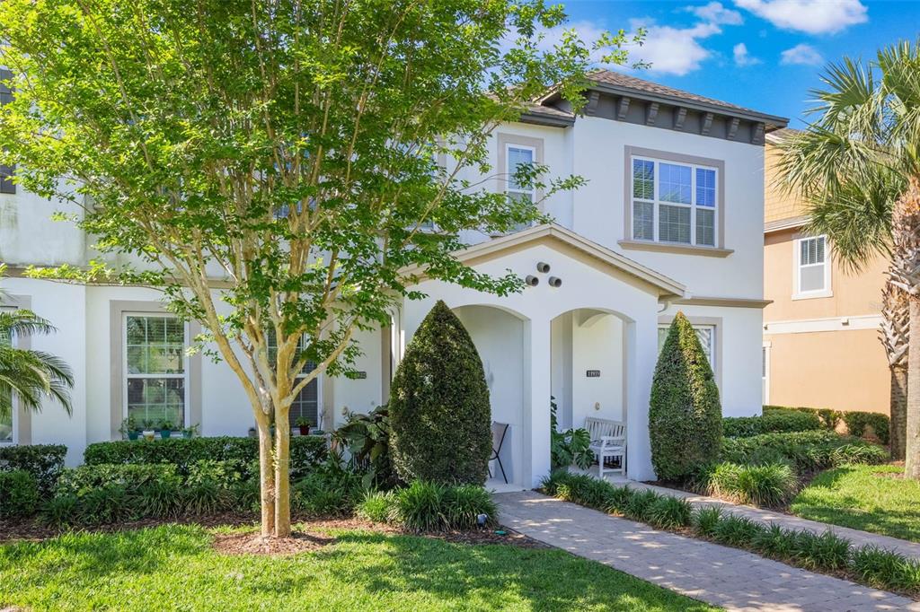 A two-story white stucco house features a covered entryway, a paved walkway, and landscaping — 11933 WATER RUN ALLEY, WINDERMERE, FL