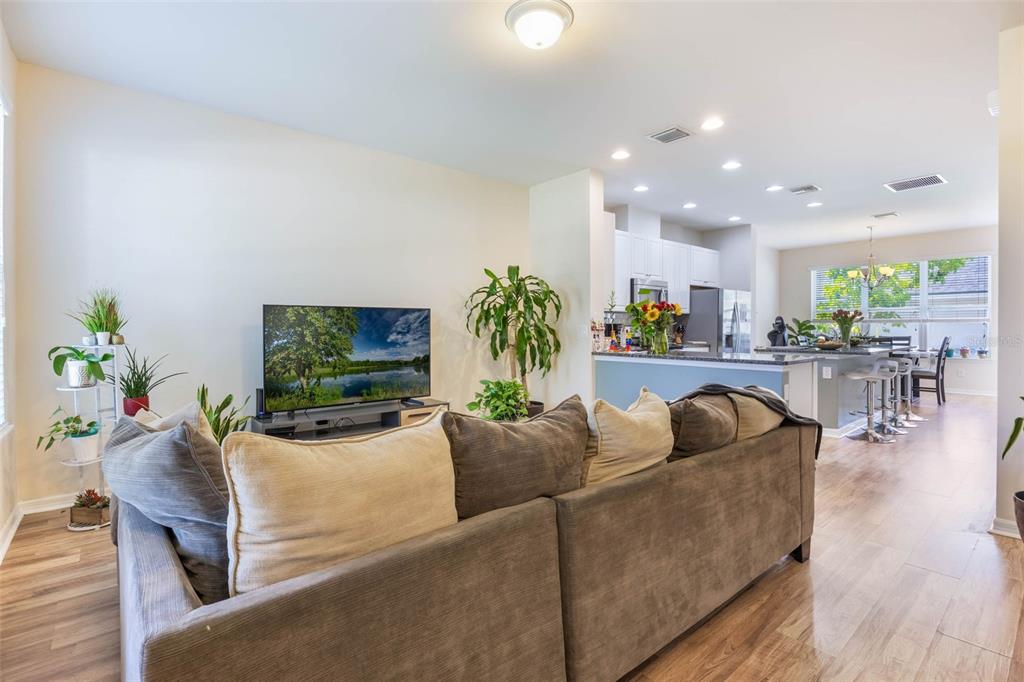 A living room with a large sofa faces a television and an open-concept kitchen — 11933 WATER RUN ALLEY, WINDERMERE, FL