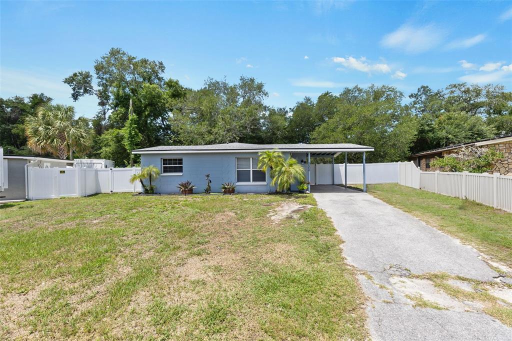 A single-story light blue house with a carport and a white vinyl fence — 5508 WHITMORE DRIVE, TAMPA, FL