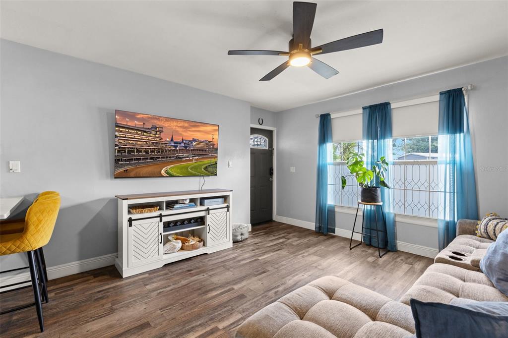 A living room features a wall-mounted television, a white media console, and a ceiling fan — 5508 WHITMORE DRIVE, TAMPA, FL