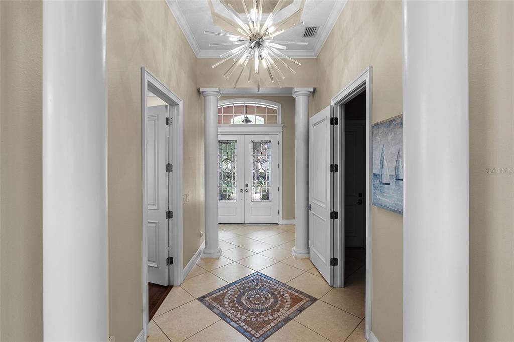 A foyer features a mosaic tile inlay, two white columns, and a modern sputnik chandelier — 9326 SAN JOSE BLVD, HOWEY IN THE HILLS, FL