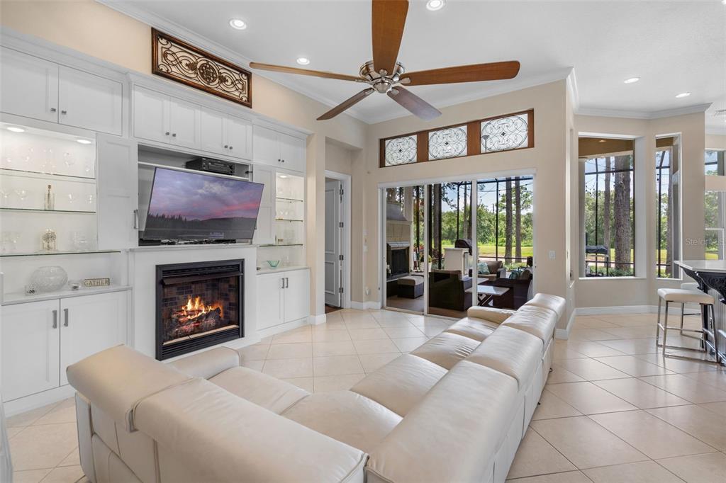 A living room features a white built-in entertainment center, a fireplace, and sliding glass doors — 9326 SAN JOSE BLVD, HOWEY IN THE HILLS, FL