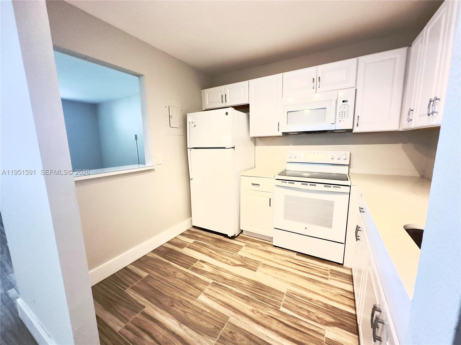 A kitchen features white cabinets, white appliances, and wood-look tile flooring — 58 Monaco B # 58, Delray Beach FL 33446, DELRAY BEACH, FL