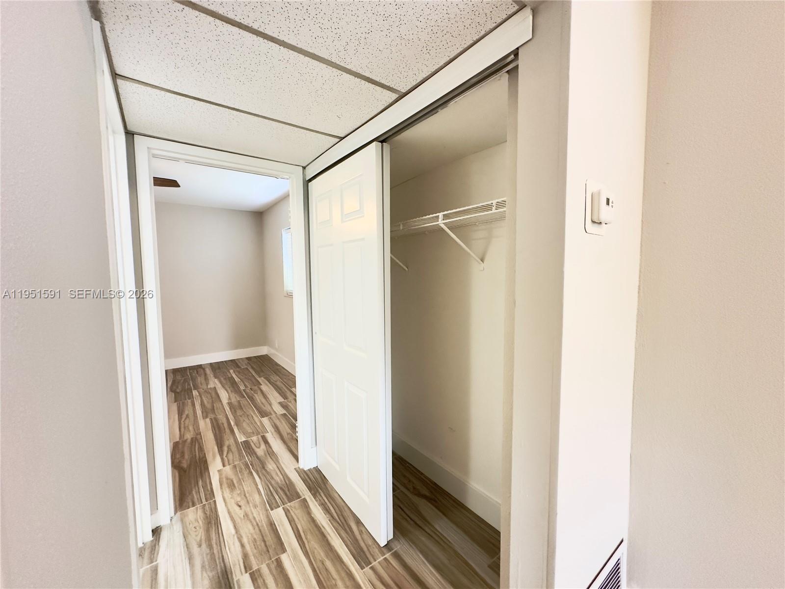 A hallway leads to a room with wood-look tile flooring and an open closet — 58 Monaco B # 58, Delray Beach FL 33446, DELRAY BEACH, FL