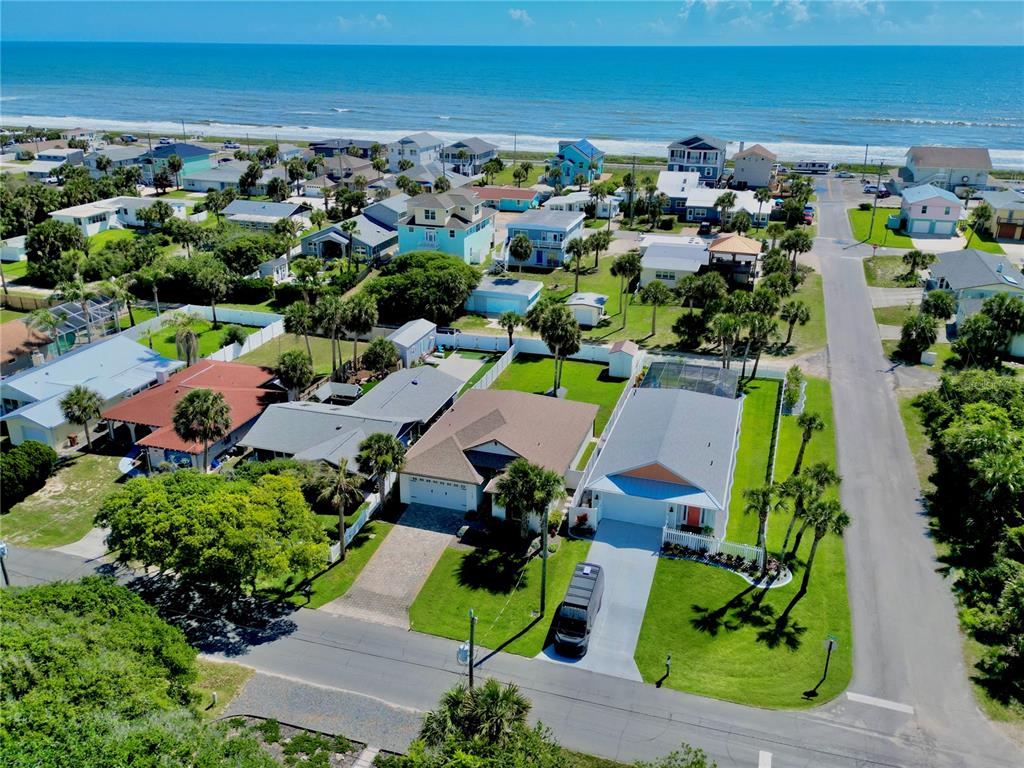 An aerial view shows a coastal neighborhood with houses, palm trees, and the ocean beyond — 1939 S DAYTONA AVENUE, FLAGLER BEACH, FL