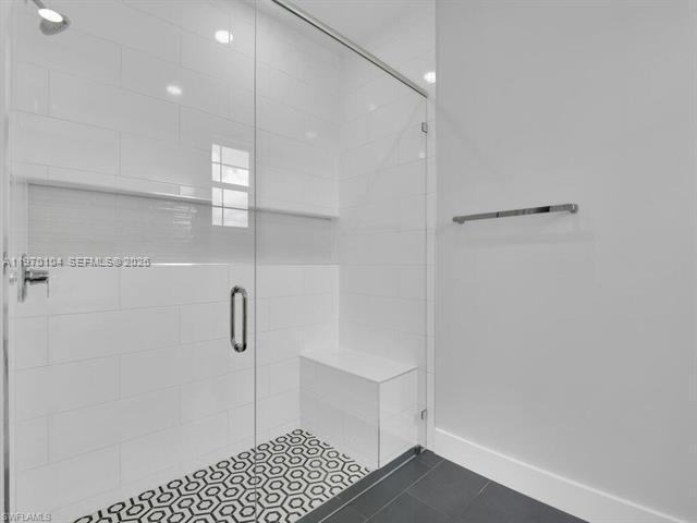A modern walk-in shower features white subway tiles, a glass door, and a built-in bench — 834/836 Motel St E, Lehigh Acres FL 33974, LEHIGH ACRES, FL