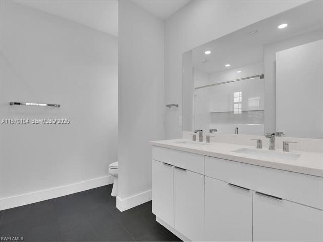A modern bathroom features a white double vanity, a large mirror, and dark floor tiles — 834/836 Motel St E, Lehigh Acres FL 33974, LEHIGH ACRES, FL