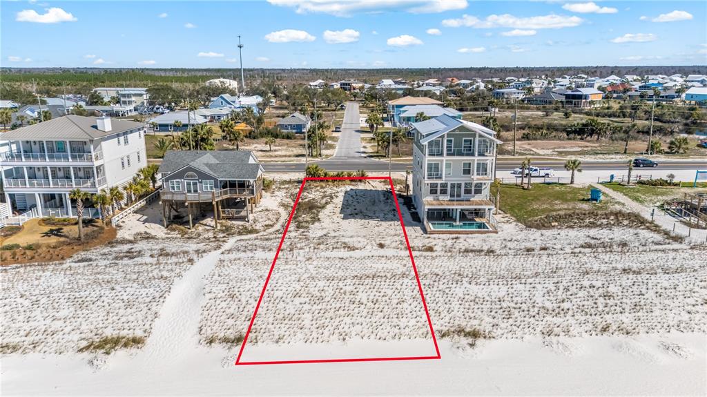An aerial view shows a vacant, sandy beachfront lot outlined in red between two houses — 1817 HIGHWAY 98, MEXICO BEACH, FL