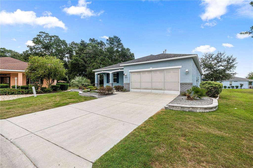 A light blue single-story house features a two-car garage and a concrete driveway — 7767 SW 80TH PLACE ROAD, OCALA, FL