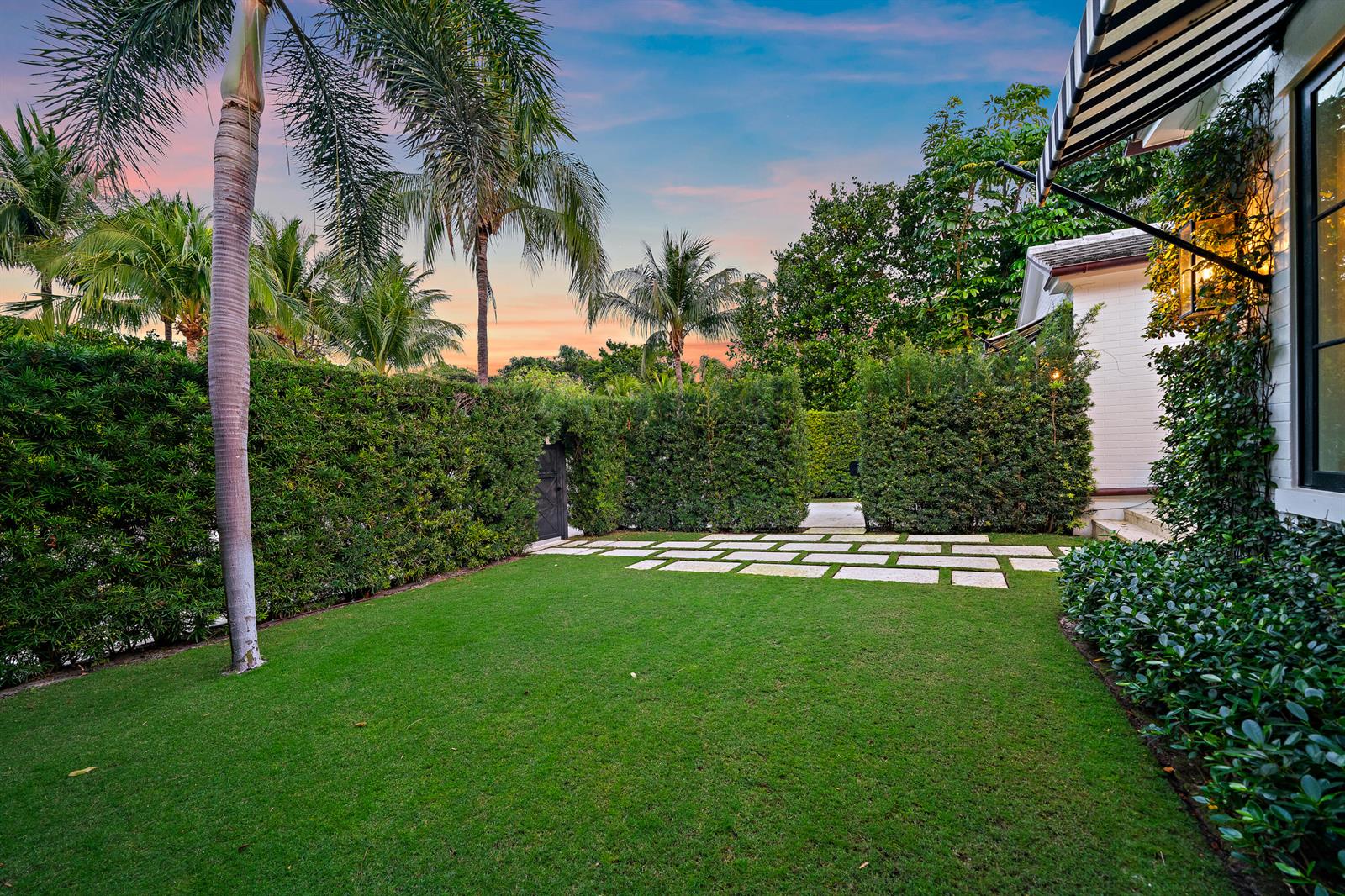 A manicured lawn features a stone paver path bordered by tall hedges and palm trees — 160 Chilean Avenue, Palm Beach FL 33480, PALM BEACH, FL