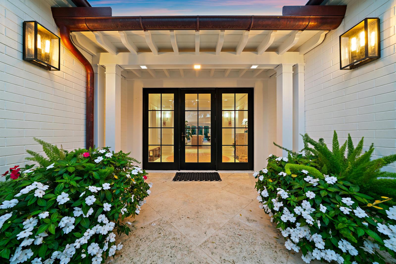 A covered entryway features a stone floor, black-framed glass doors, and two large flowering planters — 160 Chilean Avenue, Palm Beach FL 33480, PALM BEACH, FL